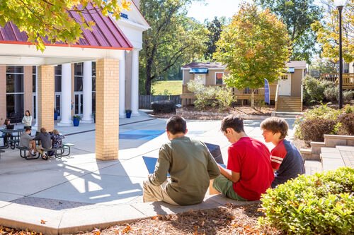 Three students working outside on laptops